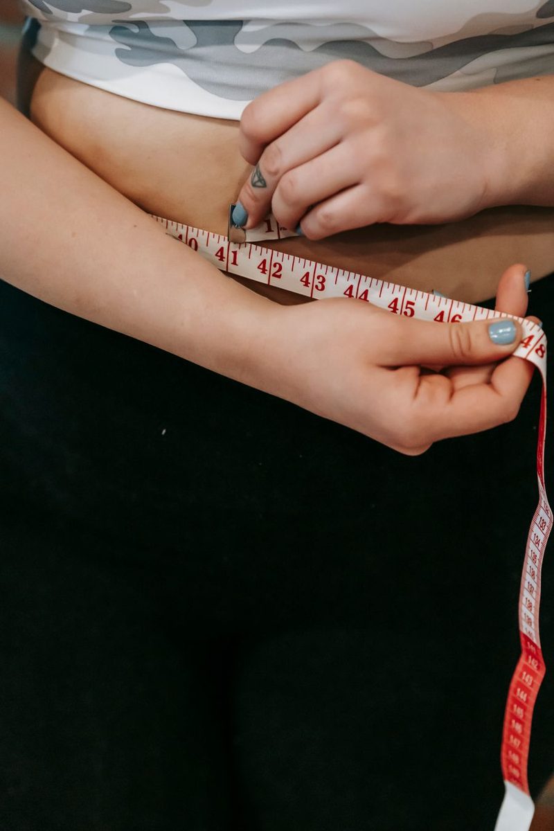 Mulher medindo a cintura, frustrada com a retenção e o inchaço